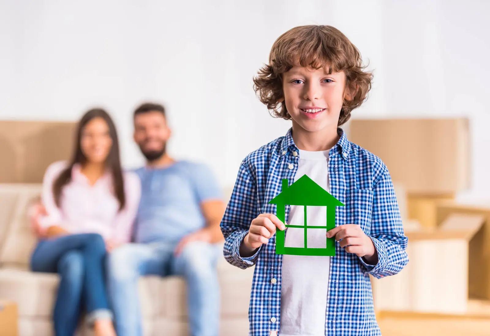 Smilende dreng med et modelhus foran sin familie